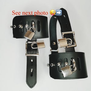 May include: Two black leather wrist cuffs with metal lock and key accents. The cuffs are secured with a buckle closure.  See next photo. 😉➡️