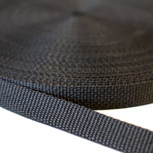 Może przedstawiać: Zbliżenie czarnego nylonowego paska, zwiniętego i pokazującego splecioną fakturę.