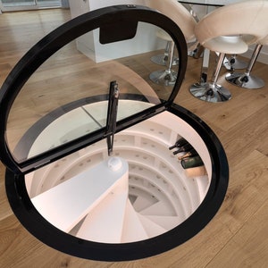 May include: A circular wine cellar with a glass door that opens to reveal a spiral staircase and shelves of wine bottles.