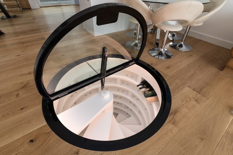 May include: A circular wine cellar with a glass door that opens to reveal a spiral staircase and shelves of wine bottles.