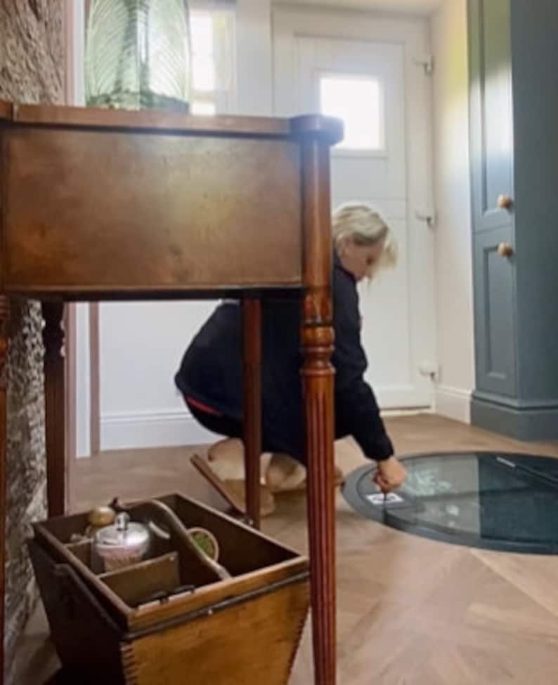 May include: A wooden table with a drawer and turned legs, a wooden box with handles, and a round glass panel in the floor.