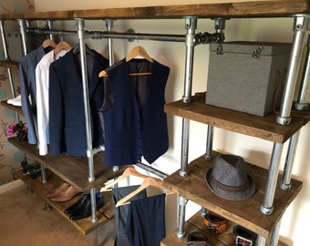 Rustic industrial open wardrobe design reclaimed timber and metal tubing. Wood and steel bespoke furniture with shelves and hanging rails.