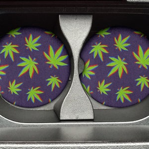 May include: Two round, purple coasters with a green and red marijuana leaf pattern.