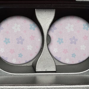 May include: Two round pink fabric coasters with a white, pink, and blue floral pattern.