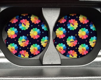 May include: Two round black coasters with a repeating pattern of colorful smiling flowers with stars on a dark blue background.
