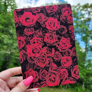 May include: A close-up image of a dark background with a pattern of red roses. The roses are arranged in a random pattern and are all in full bloom.