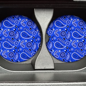 May include: Two blue and white paisley patterned car coasters. The coasters are round and have a white background with blue paisley designs.