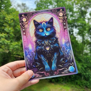 May include: A black cat with a mystical aura sits in a colorful, ornate frame. The cat has glowing blue eyes and a third eye on its forehead. The frame is decorated with stars and swirls.