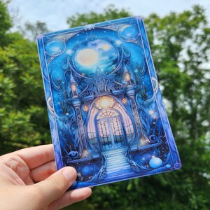 May include: A blue and white illustration of a magical gateway with a moon and stars in the background. The gateway is made of ornate metal and has a large, arched opening. The moon is full and bright, and the stars are twinkling.
