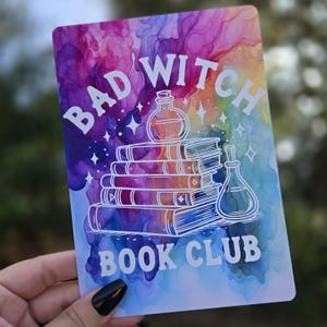 May include: A watercolor background with a rainbow of colors. The text "Bad Witch Book Club" is in white with a stack of books, a potion bottle, and stars.