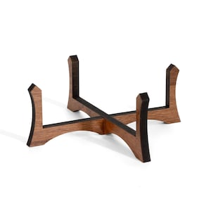 May include: A wooden stand with four legs, each with a curved top. The stand is made of dark brown wood with a black stain on the edges.