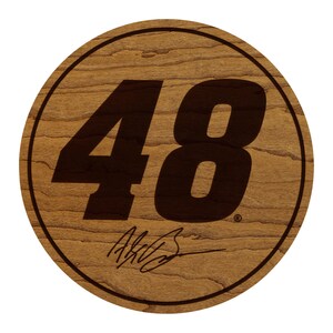 May include: A round wooden plaque with a dark brown border and a light brown wood grain background. The number "48" is prominently displayed in a bold, dark brown font. Below the number is a signature in a matching dark brown color.