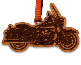 Puede incluir: Un adorno de madera con forma de motocicleta. El adorno es de color marrón y tiene una silueta negra de una motocicleta con un conductor.