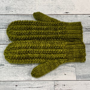 Può includere: Un paio di guanti di lana verde con una trama a coste. I guanti sono realizzati con un filato morbido e caldo e hanno un design semplice e classico.
