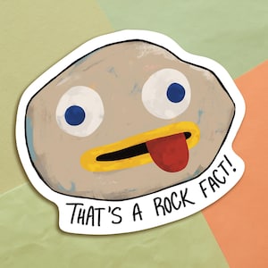 Puede incluir: Una roca de dibujos animados con un pico amarillo, ojos azules y una lengua roja que sobresale. La roca tiene un contorno blanco y el texto "That's a rock fact!" está escrito debajo.