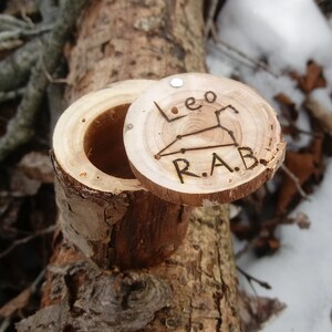 May include: A small wooden box with a hinged lid. The lid is open and shows a carved design of the constellation Leo with the initials "R.A.B."