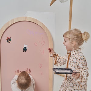 Pink arch magnetic chalkboard mounted on the wall in a Scandinavian style kids room