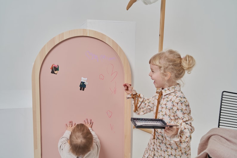 Pink arch magnetic chalkboard mounted on the wall in a Scandinavian style kids room
