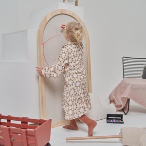 Toddler using a wooden arch magnetic chalkboard for creative play and drawing