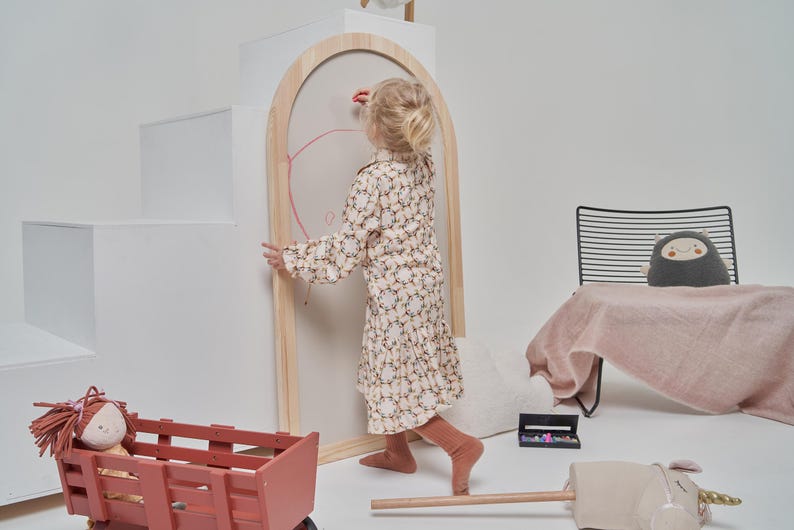 Toddler using a wooden arch magnetic chalkboard for creative play and drawing