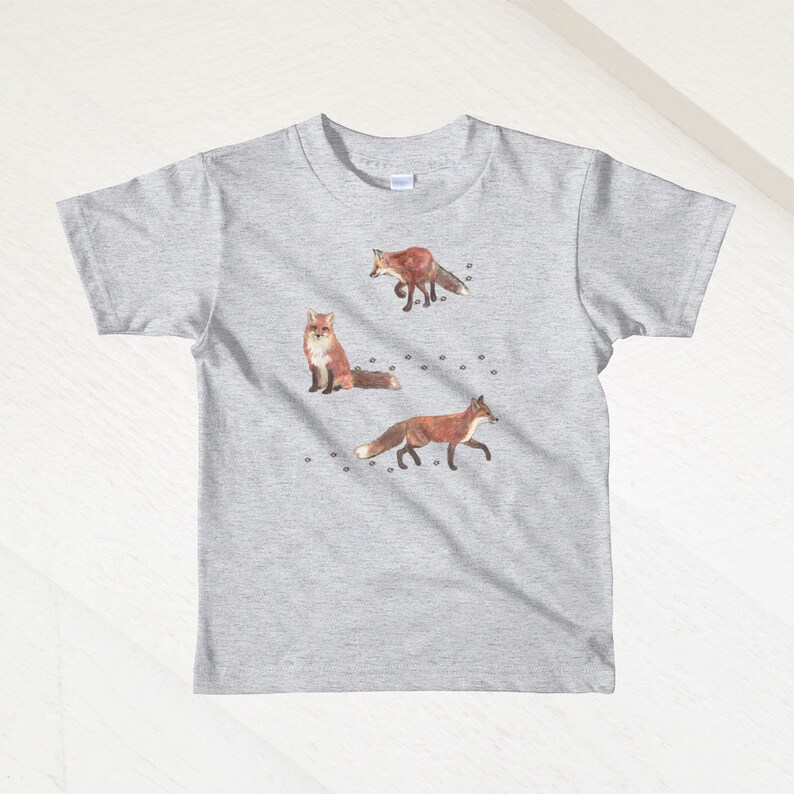 May include: A heather grey t-shirt with a design of three foxes and paw prints. The foxes are brown and orange with white accents.