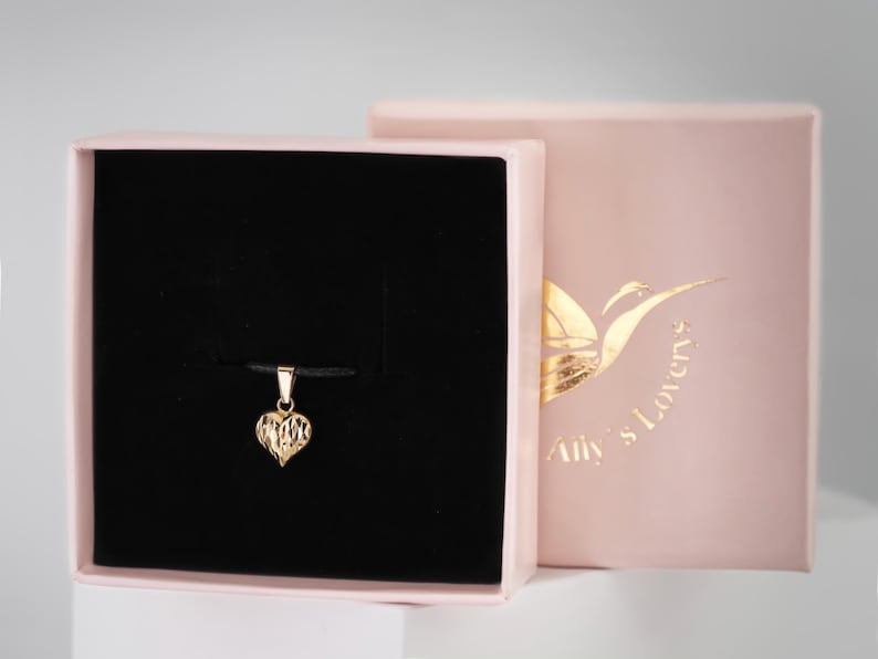 May include: A gold heart pendant necklace in a black velvet box with a pink lid. The box has the text "My Lovers" printed on the lid.