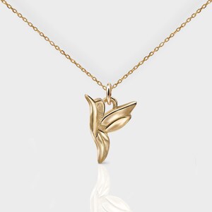 Pode incluir: Um colar de ouro com um pingente de beija-flor. O beija-flor &eacute; estilizado e tem um design detalhado.