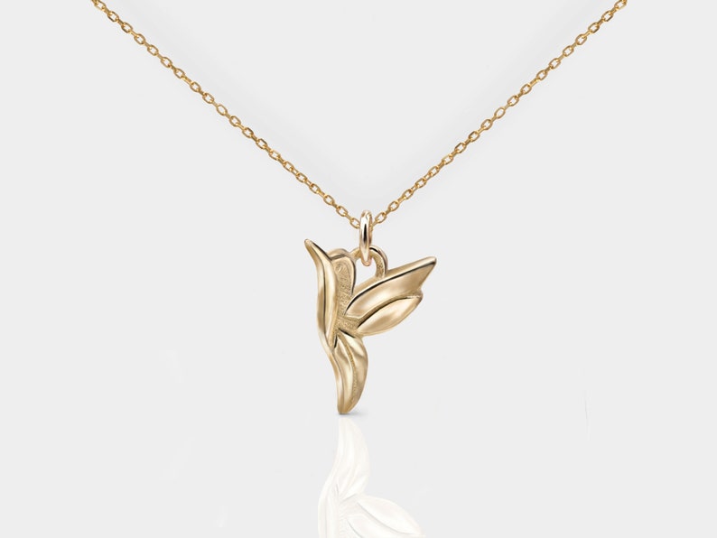 Pode incluir: Um colar de ouro com um pingente de beija-flor. O beija-flor &eacute; estilizado e tem um design detalhado.