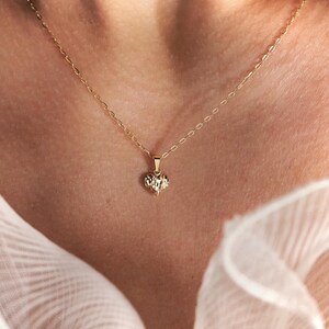 May include: A delicate gold chain necklace with a small, textured heart pendant.