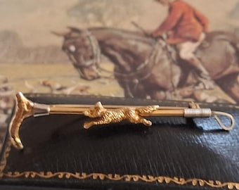 A quality stockpin - foxhunting attire. An exquisite example of English craftmanship in 9ct gold featuring a running fox and a hunting whip.