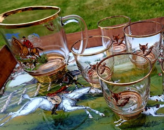 A set of six (6) glass water tumblers and matching pitcher with a fox hunting theme, featuring a fox mask, his brush and a hunting whip.