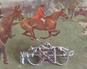 A detailed brooch of fox hunting interest, featuring a hound in close pursuit of the fox. English foxhunting costume jewellery, stock pin.