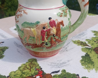 A handpainted English foxhunting pitcher made by Wedgwood featuring hunting scenes and a beautiful fox hound handle. A horse and hound jug.