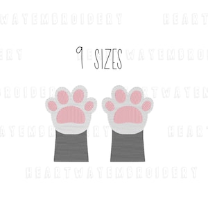 May include: Two white cat paws with pink paw pads and gray cuffs. The paws are embroidered and available in nine sizes. The text "9 SIZES" is written in black above the paws.
