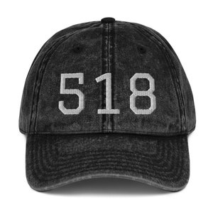 Puede incluir: Una gorra de béisbol negra de estilo vintage con el número "518" bordado en blanco en la parte delantera.