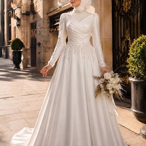 Hijab friendly modest bridal gown with high neck satin styling and graceful coverage for a Muslim wedding look