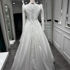 Long train satin ball gown with graceful movement, pearl beaded details and timeless bridal elegance