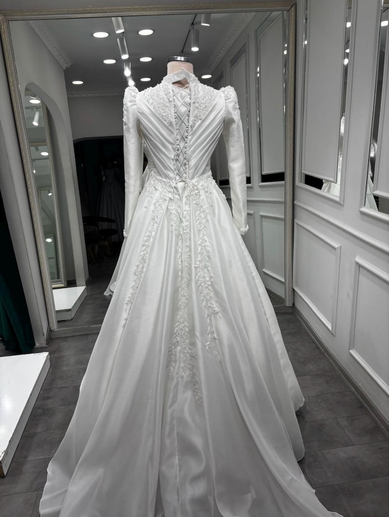 Long train satin ball gown with graceful movement, pearl beaded details and timeless bridal elegance