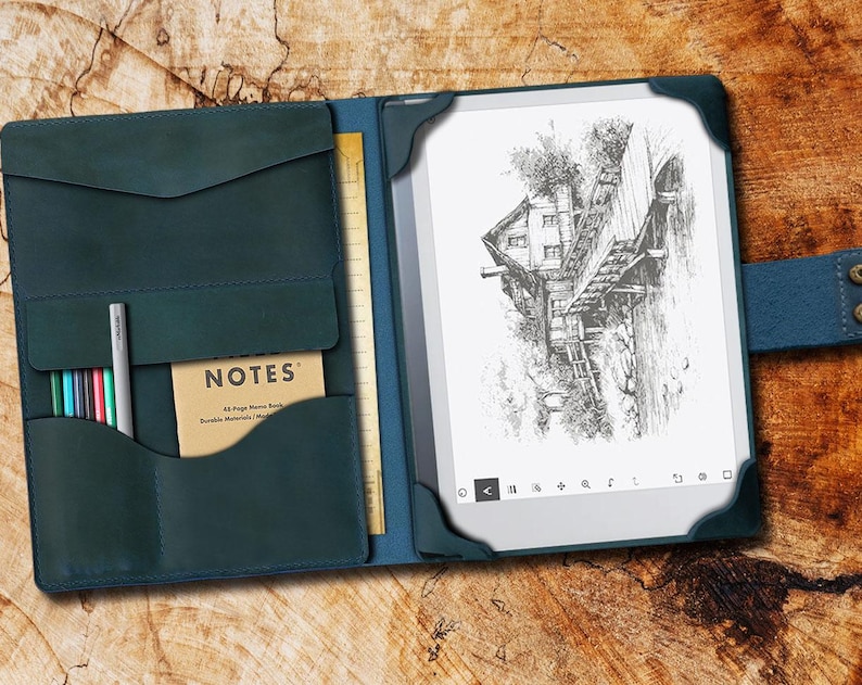 May include: A teal leather notebook cover with a built-in pocket for pens and a notepad. The cover is open to reveal a black and white e-reader with a drawing of a house on a bridge.