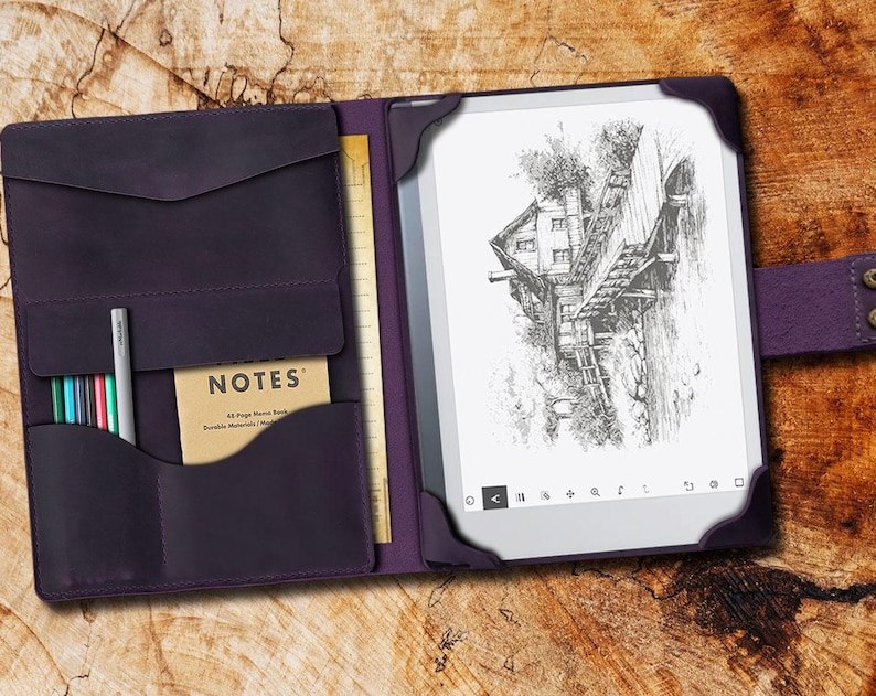 May include: A purple leather folio case with a built-in notepad and pen holder. The case is open to reveal a black and white e-reader with a drawing of a house on a bridge. The text "NOTES" is visible on the notepad.