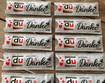 May include: A collection of gray felt wrappers, each holding a chocolate bar. The wrappers are decorated with red hearts and the German word "Danke" (Thank You). The text "du" is also visible.