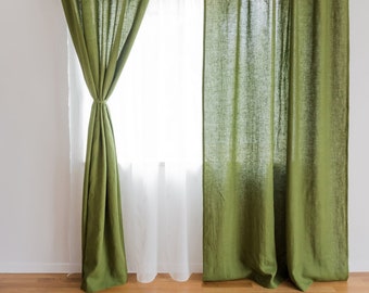 May include: A pair of green linen curtains with a white sheer curtain behind them. The curtains are hung on a metal rod and are pulled back to reveal the window.