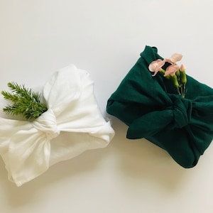 白または緑のリネン風呂敷。ギフトラッピングクロス。風呂敷。結婚式やクリスマス用のナチュラルで再利用可能なギフトラップ。