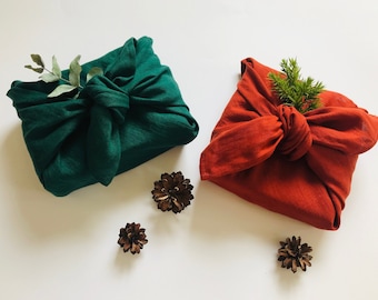 Linen gift wrapping cloth for Christmas. Furoshiki wrapping cloth in red or green colours. Sustainable fabric gift wrap for holidays.