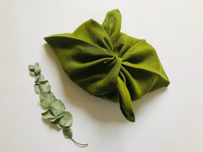 Puede incluir: Una bolsa de tela verde atada con un nudo, ideal para guardar objetos peque&ntilde;os. La bolsa est&aacute; hecha de un material suave y natural y es una alternativa sostenible a las bolsas de pl&aacute;stico.