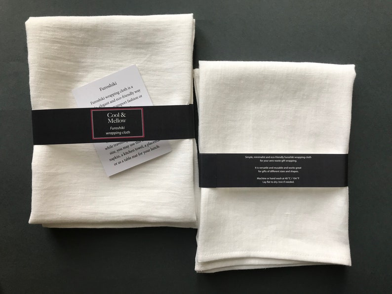 May include: Two white linen furoshiki wrapping cloths, one folded and one flat, with black labels that read "Cool & Mellow Furoshiki wrapping cloth".