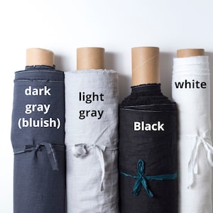 May include: Four rolls of fabric in different colors: dark gray (bluish), light gray, black, and white. The fabric is rolled up and tied with a ribbon.
