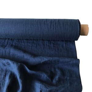 Puede incluir: Un rollo de tela de lino azul oscuro. La tela está tejida con una textura sutil y tiene una sensación suave y natural.