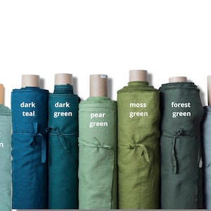 K&ouml;nnte beinhalten: Sieben vertikale Stoffrollen in verschiedenen Gr&uuml;n- und Blaut&ouml;nen. Die Rollen sind mit folgendem Text beschriftet: Mint green, dark teal, dark green, pear green, moss green, forest green und khaki green. Jede Rolle ist mit einem Stoffband gebunden.