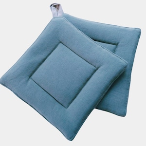 May include: Two blue quilted pot holders with a loop handle. The pot holders are made of a soft, textured fabric.